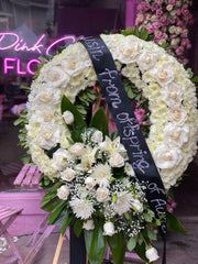 Serene white and green floral spray arrangement styled in a timeless circular design for remembrance occasions