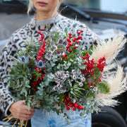 Vibrant Christmas bouquet with red berries, pinecones and frosted foliage, styled for festive holida