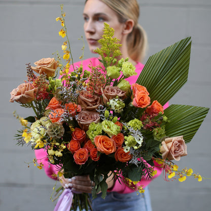 Cheerful bouquet showcasing radiant yellow tones with soft pink accents, arranged in a lively and elegant style
