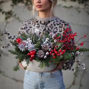 Festive floral arrangement showcasing silvery pinecones, blue thistle and lush greenery in a celebra