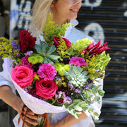 Luxurious floral arrangement styled with vibrant roses and lush green succulents, ideal for romantic occasions and upscale gifting